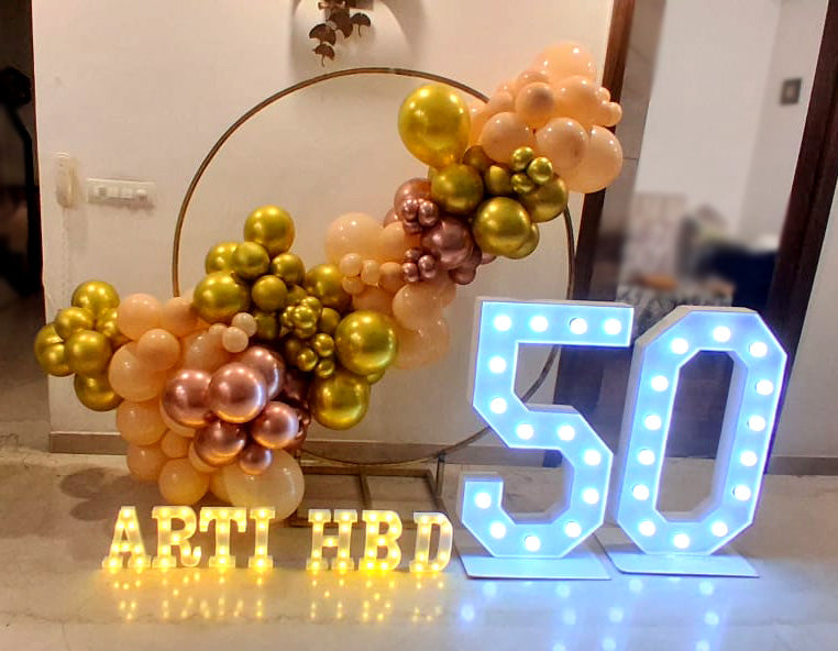 50th birthday balloon ring decoration with gold peach and rose gold balloons, marquee number lights and name signage by Funzoop Gurgaon