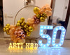 50th birthday balloon ring decoration with gold peach and rose gold balloons, marquee number lights and name signage.