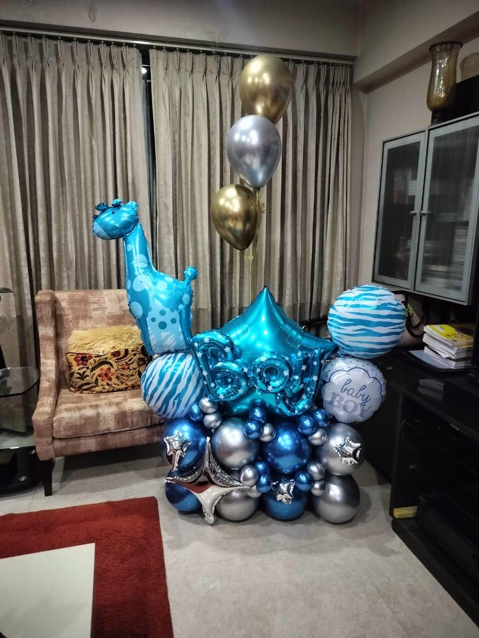 Blue giraffe and BABY letter balloons arranged on a navy and silver balloon base.