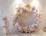 Pink, white and gold baby arrival balloon ring with butterflies, gold stars and stacked BABY boxes.