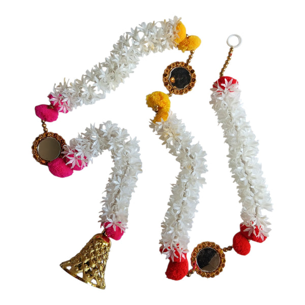 White floral Diwali door hanging with colourful pom-poms, round mirrors in gold frames and a decorative bell at the end.