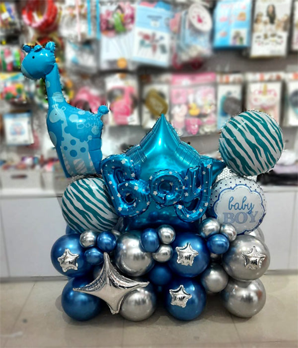 Blue giraffe foil beside baby lettering, star foils and blue and silver balloons.