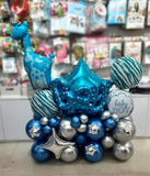 Blue giraffe foil beside baby lettering, star foils and blue and silver balloons.