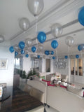 Wide view of a living room decorated with blue and silver-toned ceiling balloons and cascading