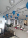 Wide view of a living room with blue and silver-toned ceiling balloons and cascading curling ribbons.