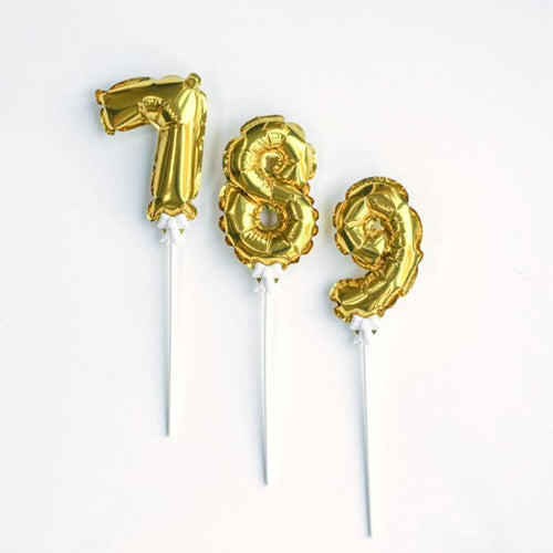 Gold mini number foil balloons on sticks used as cake toppers