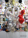Silver 60 number balloons with silver and confetti balloons beside three red heart foil balloons.