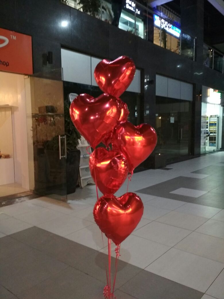 Six red heart-shaped foil balloons arranged as a helium bouquet with curling ribbons delivered by Funzoop Party Store.