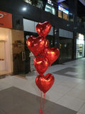 Six red heart-shaped foil balloons arranged as a helium bouquet with curling ribbons delivered by Funzoop Party Store.